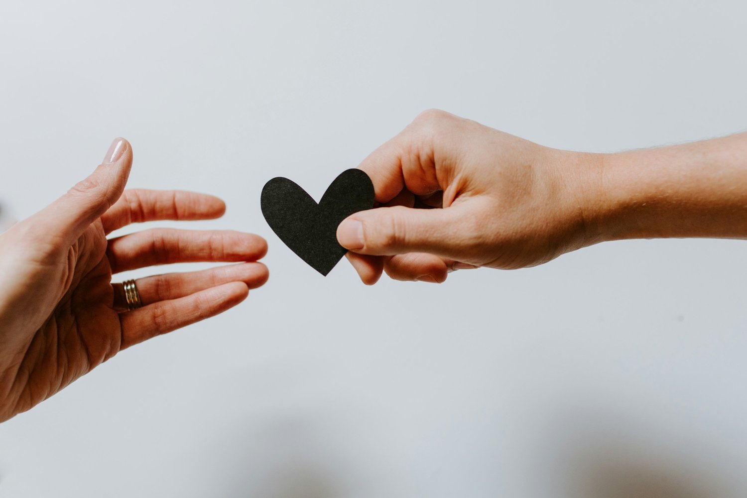 Two hands passing a paper heart